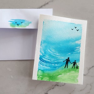 Tarjeta de felicitación en blanco pintada a mano. Parte de la serie "Juntos". Dos personas disfrutando de un paseo juntas con una hermosa puesta de sol.