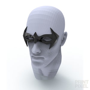 May include: A black superhero mask with a stylized wing design, resting on a mannequin head. The mask covers the eyes and has a glossy finish. The head is a light grey colour, and the background is white.