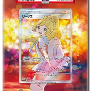 May include: A framed Pok&eacute;mon trading card featuring a character illustration. The card is encased in a clear acrylic holder with a red PSA label at the top. The card's artwork depicts a blonde-haired girl in a pink and white outfit. The background shows a sunset.