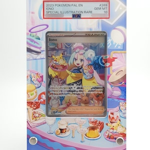 May include: A clear acrylic display case with a Pokemon card inside. The card features the character Iono, with text that reads "2023 Pokemon Pal En Iono Special Illustration Rare." The case has a colorful, illustrated background with food and drink.