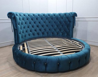 May include: A teal blue round bed with a tufted headboard and a slatted base. The headboard has a curved shape and is accented with decorative bows.