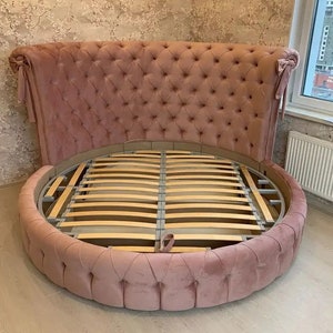 May include: A round pink tufted bed frame with a slatted base. The headboard is tall and curved with tufted upholstery.