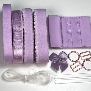 Peut inclure: Un ensemble de bretelles de soutien-gorge lilas, une fermeture à crochets et à œillets de soutien-gorge lilas, un nœud lilas, deux bandes élastiques transparentes, deux anneaux métalliques argentés et deux crochets métalliques dorés.