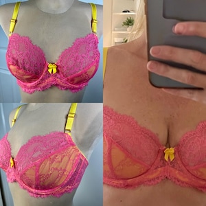 May include: A bright pink lace bra featuring yellow adjustable shoulder straps and a small yellow bow at the center gore. The cups are constructed with floral patterned lace overlaying a solid pink fabric, finished with a scalloped edge.