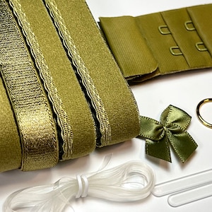 May include: A set of olive green bra strap extenders with a matching bow and clear elastic. The extenders have three rows of hooks and eyes.