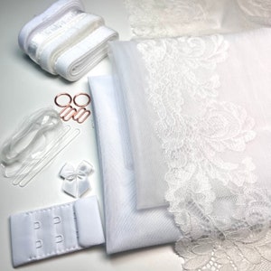May include: White bridal lingerie making kit with lace trim, tulle fabric, elastic straps, bra clasp, and clear plastic rings.