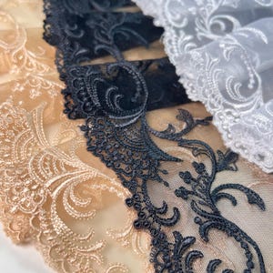 Puede incluir: Tres galones de encaje diferentes en beige, negro y blanco. El encaje es delicado y presenta un patrón floral.