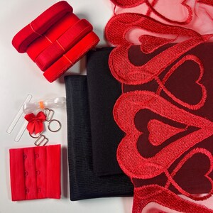 May include: A set of red lingerie making supplies including lace trim, elastic, hook and eye closures, and black fabric.