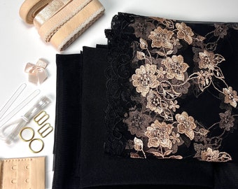 May include: A set of black fabric, lace, and mesh for crafting a garment. The set includes a piece of black fabric with a floral lace trim, a piece of black mesh fabric, and a piece of black fabric with a floral design. The set also includes a beige bra strap, a beige ribbon, and a beige bow.