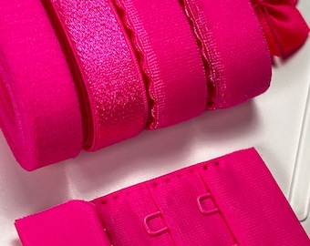 May include: A set of pink bra straps and a pink bra extender with three hooks. The straps are made of different materials, including elastic and lace.