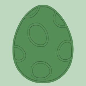 May include: A green egg-shaped design with a series of oval and curved indentations. The egg shape is a solid green color, with a lighter green background. The design is a simple, graphic illustration.