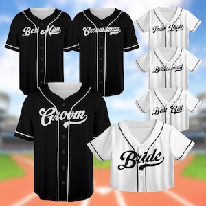 May include: Set of 10 baseball jerseys with various wedding party titles, including "Groom", "Bride", "Best Man", "Best Girl", "Groomsman", "Bridesmaid", and "Team Bride". The jerseys are black and white with white lettering.