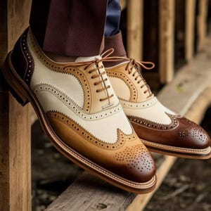 May include: A pair of brown, tan, and white leather brogue shoes with decorative stitching and laces.