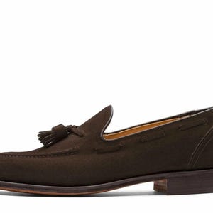 May include: Brown suede tassel loafers with a leather sole.