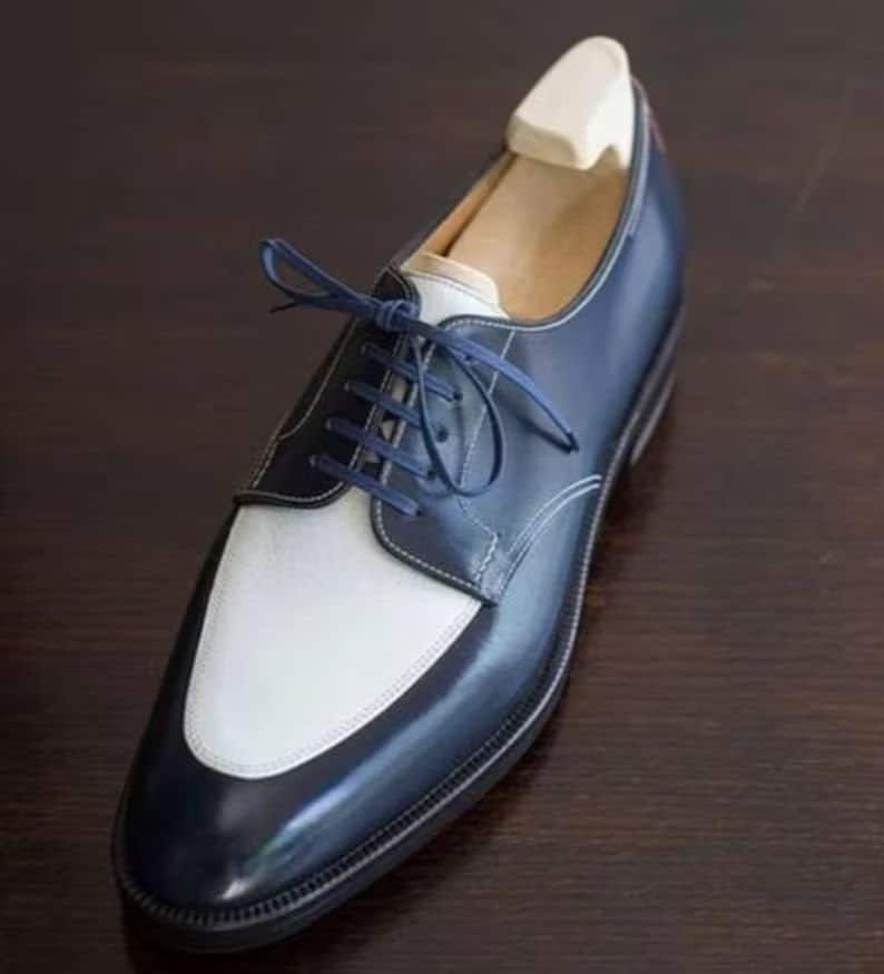 May include: A pair of blue and white leather dress shoes with lace-up closure. The shoes have a pointed toe and a polished finish.