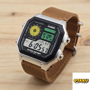 May include: A Casio digital watch with a black face, silver bezel, and brown leather strap. The watch displays the time, date, and world map. The text on the watch face includes "SALARMS", "CASIO", and "10 YEAR BATTERY".