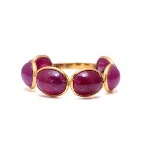 Op de afbeelding: Een gouden ring met zes ovale robijnstenen die in een bezel-setting zijn gezet.
