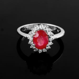 Peut inclure: Une bague en argent avec un gros rubis ovale entouré d'un halo de petits diamants.