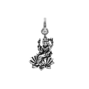 May include: A silver-colored charm depicting a seated deity figure, possibly Lakshmi, on a lotus flower base. The charm has intricate details and a loop for attaching to a necklace or bracelet. The figure is in a meditative pose.