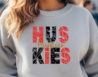 May include: Gray sweatshirt with a distressed black and red graphic that says "HUSKIES" with the word "Huskies" in gold lettering.
