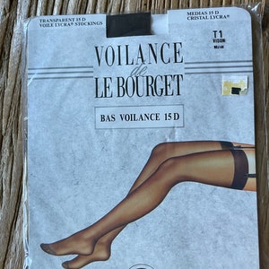Puede incluir: Paquete de medias transparentes "VOILANCE de LE BOURGET", con una ilustración de piernas que llevan las medias. El paquete incluye el texto "LYCRA" y "MADE IN FRANCE". El texto "BAS VOILANCE 15 D" también es visible.