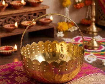 Puede incluir: Una cesta de metal en tono dorado pulido con un borde festoneado y un asa fina y arqueada. La superficie exterior está decorada con un patrón repetitivo de pequeñas hendiduras circulares en relieve y motivos florales alrededor.