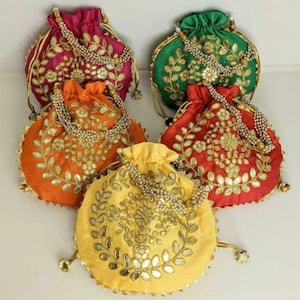 May include: Five round drawstring pouches in magenta, green, orange, red, and yellow satin fabric. Each pouch features gold-toned metallic embroidery in a leaf and floral pattern, accented with small mirrors and a beaded handle made of white pearls.