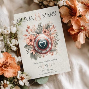 Può includere: Un invito di nozze con i nomi "Olivia & Mark". Il design include elementi floreali e botanici, e uno scudo con un cuore. La data è il 25 settembre 2025, alle 14:30.