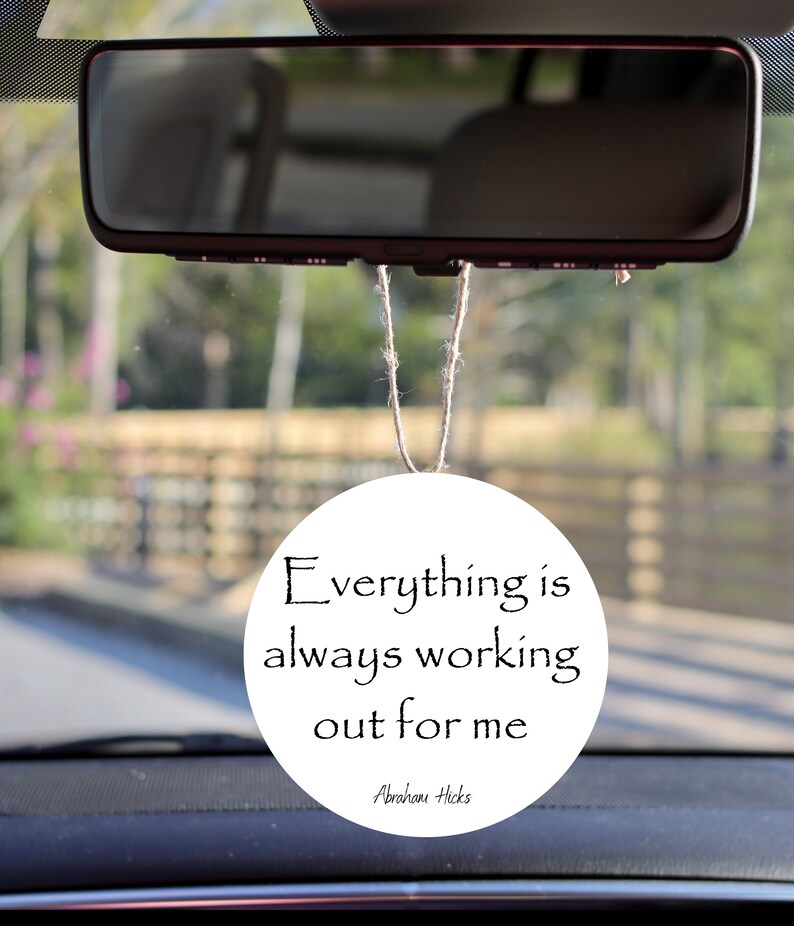 May include: White round car air freshener with the text "Everything is always working out for me" and the name "Abraham Hicks" at the bottom.