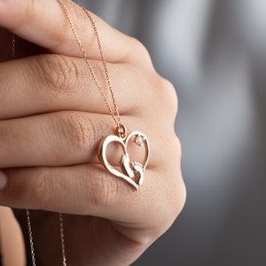 May include: A gold heart-shaped necklace with a small diamond and two baby footprints inside the heart.