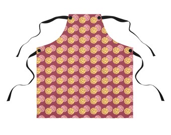 May include: A red apron with a pattern of pink and yellow concha bread. The apron has adjustable straps.