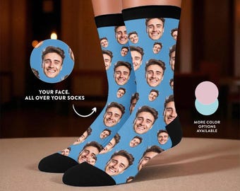 May include: A pair of custom socks with a light blue background and a repeating pattern of a smiling face. The socks have black heels and toes, and black bands at the top. Text on the image reads "YOUR FACE. ALL OVER YOUR SOCKS."