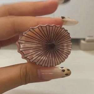 May include: A white ceramic mug with a black handle and the text "But First, Coffee" in a bold, black font. The mug is set against a blurred background, suggesting a cozy setting.