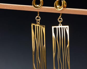 May include: A pair of gold-toned earrings with a rectangular design featuring a wavy, abstract pattern. The earrings are suspended from a crescent-shaped hook.