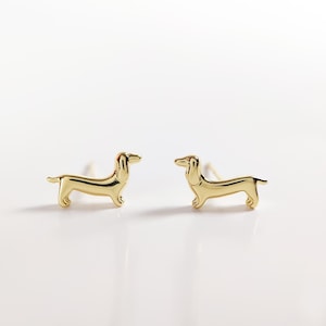 May include: A pair of gold-toned dachshund dog stud earrings. The earrings are small and delicate, and they would make a great gift for any dog lover.