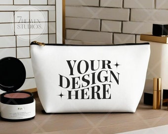 May include: White zippered makeup bag with black text that reads "YOUR DESIGN HERE" and two small stars on either side of the text.