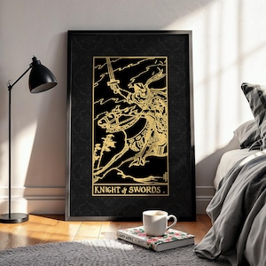 May include: A framed art print with a gold illustration of a knight on horseback, holding a sword, set against a black background. The text "KNIGHT of SWORDS" is at the bottom. The print is displayed on a wall, leaning against a bed.