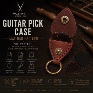 May include: A brown leather guitar pick case with a brass snap button closure and a circular metal key ring. The case is open, revealing a dark tortoiseshell guitar pick inside. Additional guitar picks are placed on the surface nearby.