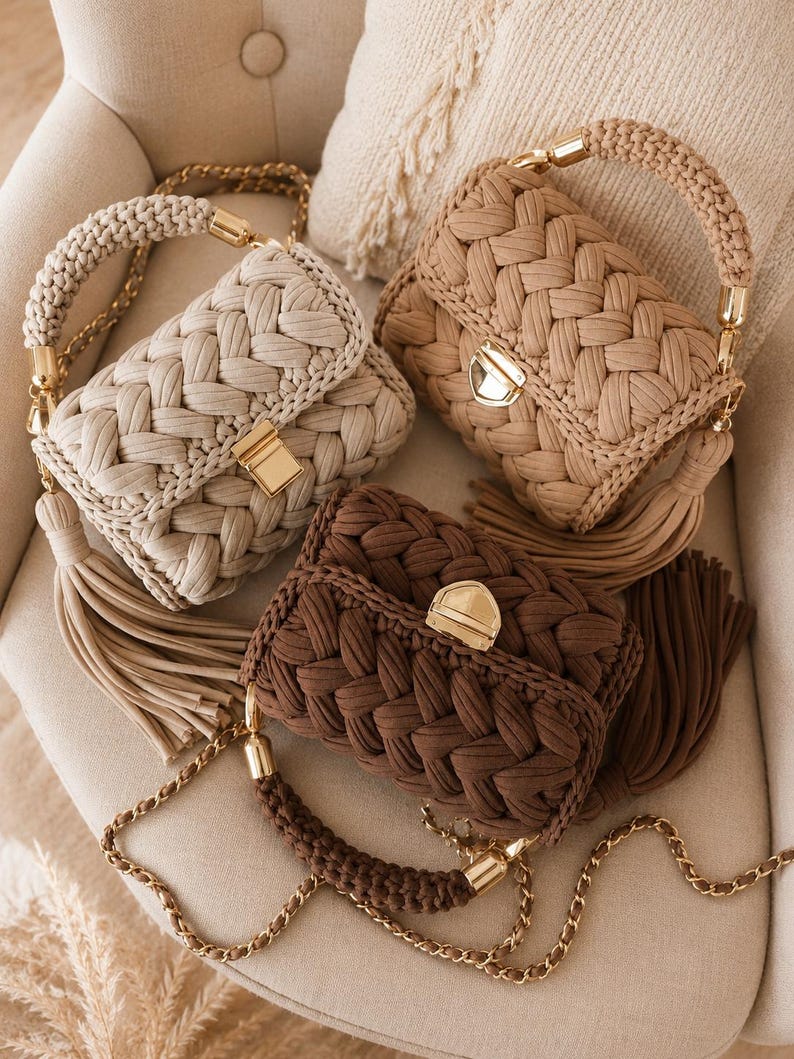 May include: Three rectangular handbags featuring a thick braided fabric texture in cream, beige, and dark brown. Each bag includes a gold-tone metal clasp, a matching braided top handle with gold hardware, a long chain shoulder strap, and a side tassel.