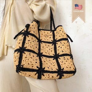 Puede incluir: Un bolso tote grande de crochet con cuadrados negros y beige. El bolso tiene dos asas negras.