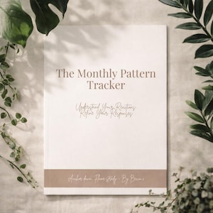 May include: A white journal titled "The Monthly Pattern Tracker" with brown text and a brown band at the bottom. The journal's text includes "Understand Your Reactions, Refine Your Responses" and "Anchor down. Flame steady - By Becca x". Green plants frame the journal.