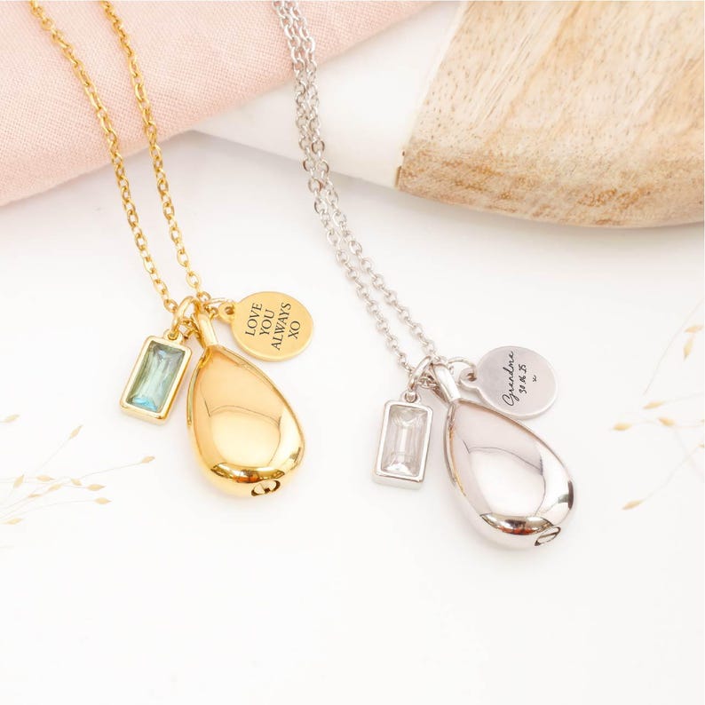 Gold and silver teardrop urn necklaces with birthstones and personalised tags shown side by side