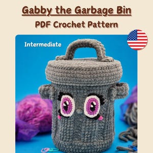Op de afbeelding: Een grijze gehaakte vuilnisbak met een handvat, met een cartoongezicht met roze en witte details. De tekst "Gabby the Garbage Bin PDF Crochet Pattern" wordt weergegeven. De moeilijkheidsgraad is "Intermediate".