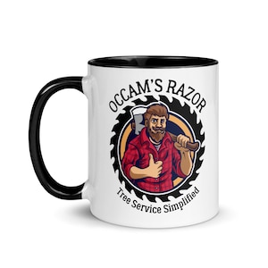 May include: White ceramic mug with a black rim and handle. The mug features a cartoon illustration of a lumberjack with a beard holding an axe. The illustration is surrounded by a black circle with the text "OCCAM'S RAZOR Tree Service Simplified".