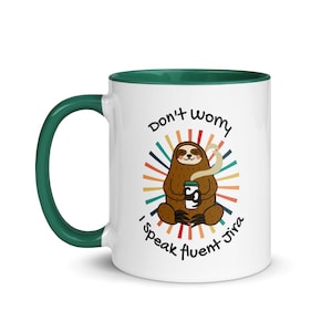 Puede incluir: Taza de café de cerámica blanca con un borde verde. La taza presenta un perezoso de dibujos animados sosteniendo una taza de café con el texto "No te preocupes, hablo Jira con fluidez" en un diseño retro de sol colorido.