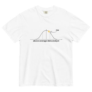 Op de afbeelding: Wit T-shirt met een zwart-witte illustratie van een klokcurve met een gele ster bovenaan. De tekst "ik" staat boven de ster met een pijl die erop wijst. De tekst "bovengemiddelde data-analist" staat onder de klokcurve.