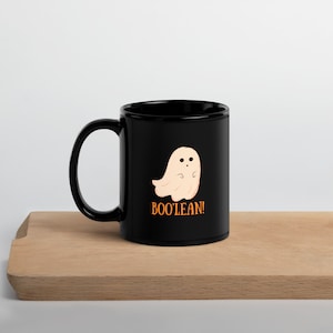 May include: Black ceramic coffee mug with a white ghost illustration and the text "BOO'LEAN!" in orange.