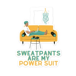 Könnte beinhalten: Aufkleber mit einer Illustration einer Person, die einen Laptop auf einem gelben Sofa benutzt. Ein kleiner Tisch hält eine Kaffeetasse und ein Buch. Der Text "SWEATPANTS ARE MY POWER SUIT" wird darunter angezeigt.
