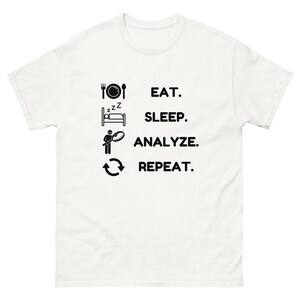 Peut inclure: T-shirt blanc avec du texte noir et des icônes qui disent : "Manger. Dormir. Analyser. Répéter."