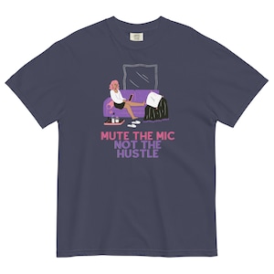 May include: A purple t-shirt featuring a graphic of a woman sitting on a sofa with a laptop. The text "Mute the mic not the hustle" is printed on the shirt.